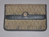 un sac à main beige et noir orné d'un monogramme, posé sur une surface blanche