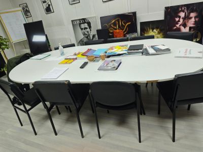 une table blanche avec des chaises noires et des tableaux accrochés au mur