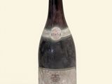 une vieille bouteille de vin posée sur une surface blanche