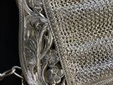 an old silver purse with a chain around it on a black surface