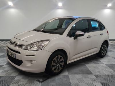 la petite voiture blanche est garée sur un sol en damier