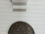 a silver coin sitting on top of a white table next to a white tag