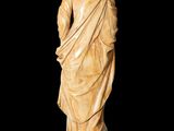 a statue of a man in a robe standing on a black surface
