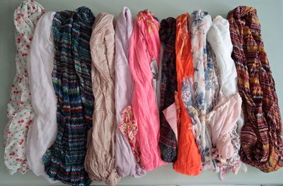 many different types of scarves hanging on a wall