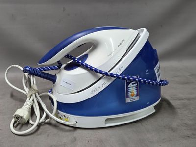un fer à repasser à vapeur bleu et blanc posé sur une surface grise
