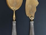 pair of silver plated serving utensils on a black background
