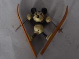 a small mickey mouse on a pair of skis hanging on a wall