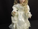 porcelain doll of a blonde haired girl in a white dress