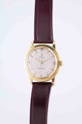 a close up of a watch on a white surface with a brown strap