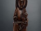 une vieille statue en bois représentant une femme assise sur une chaise