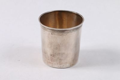 une tasse en argent posée sur une surface blanche