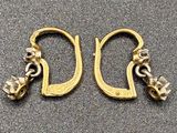 two pairs of gold earrings on a gray surface