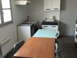 a table and chairs in a kitchen with a clock on the wall