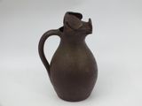 a brown vase with a cat on it on a white surface