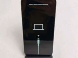a black cell phone with a charging cable attached to it
