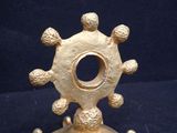 a small gold object on a stand on a blue surface