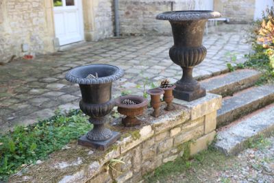 deux vases posés sur un mur de pierre, à côté d'un mur de briques
