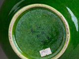 a green vase with a tag on it sitting on a table