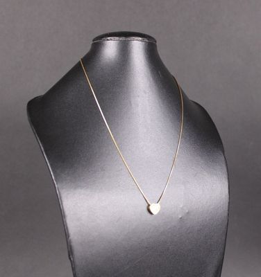 un collier en or sur un mannequin, orné d'un pendentif en forme de cœur