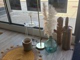 une table sur laquelle se trouvent un vase et un tapis, placée devant une fenêtre