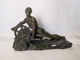 statue en bronze représentant une femme assise sur un rocher avec un chien