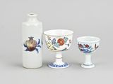three vases and a cup sitting next to each other on a table