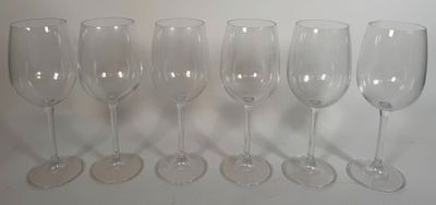 six verres à vin vides alignés sur une surface blanche