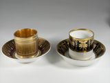 two cups and saucers are sitting on a white surface