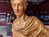 a gold statue of a man sitting on a bench