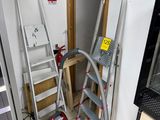 Plusieurs échelles sont empilées les unes sur les autres dans une pièce.
