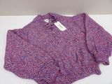 pink and purple sweater on a white table with a tag on it