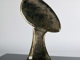 bronze sculpture of a football shaped object on a black surface
