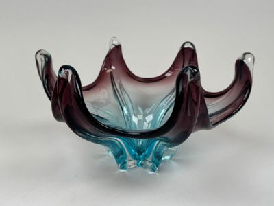 un bol en verre violet et bleu posé sur une surface blanche