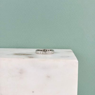 un gros plan d'une bague en diamant posée sur un bloc de marbre