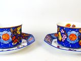 two cups and saucers sitting on a white table