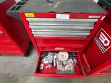 une boîte à outils rouge contenant des outils, dans un garage