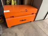 an orange tool box sitting on top of a cement floor next to a door