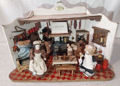 une maison de poupées miniature avec des poupées à l'intérieur, posée sur une table