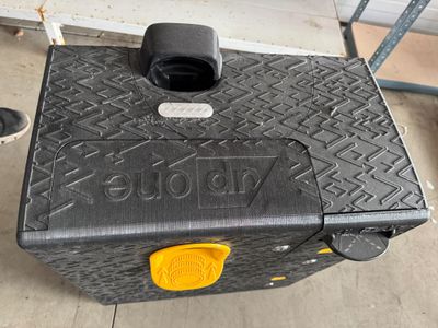 une valise noire avec une poignée jaune posée par terre