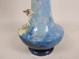 a blue vase with a bird on it sitting on a table