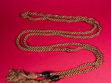 a close up of a brown rope with a black handle on a pink background