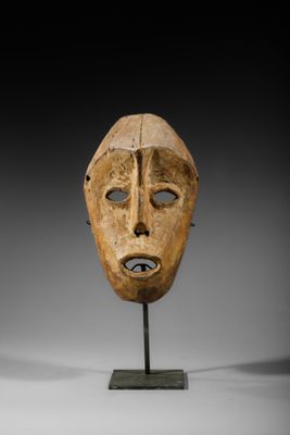 un masque en bois sur un support avec un fond noir