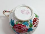 a white tea pot with a floral design on it