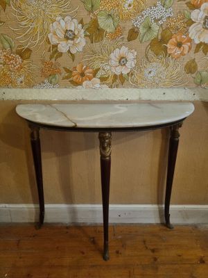 a small table with a marble top in front of a wallpapered wall