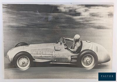 a black and white photo of a man driving a race car
