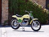 une moto tout-terrain jaune garée devant un bâtiment en pierre