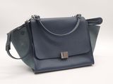 un sac à main bleu muni d'une poignée en métal sur fond blanc