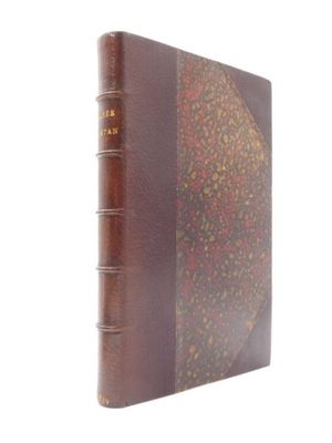 un vieux livre à la couverture brune posé sur une surface blanche