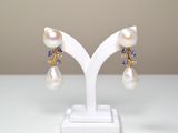 paire de boucles d'oreilles en perles et tanzanite, présentée sur un présentoir blanc