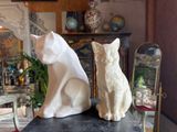 two statues of cats sitting on a table in a living room